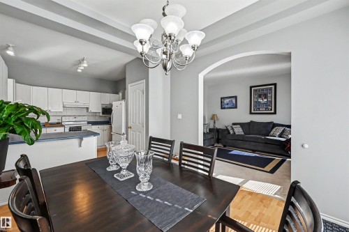White kitchen cabinetry, tray ceiling, arched doorway, and wood-finish flooring - 8513 156 Avenue Nw, Edmonton, AB 
