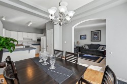White kitchen cabinetry, tray ceiling, arched doorway, and wood-finish flooring - 