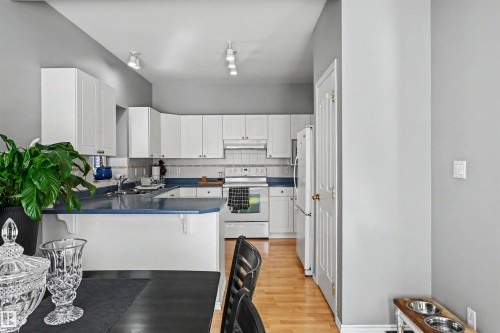 Kitchen featuring white cabinetry, a light-colored tile backsplash, and a built-in oven range - 8513 156 Avenue Nw, Edmonton, AB 