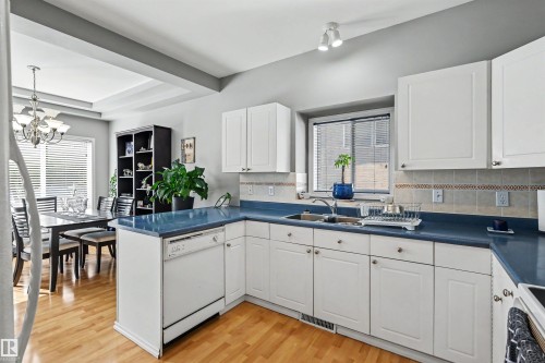Kitchen featuring white cabinetry, blue countertops, tile backsplash, and a built-in dishwasher - 8513 156 Avenue Nw, Edmonton, AB 