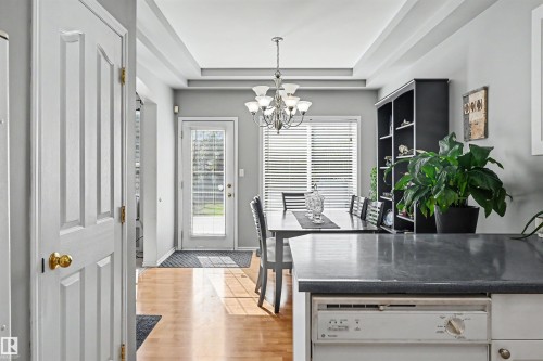 Tray ceiling with a chandelier, wood-finish flooring, and a glass-paneled exterior door - 8513 156 Avenue Nw, Edmonton, AB 
