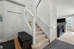 Carpeted staircase with white railings, tile flooring, and a fireplace with a mantel - 