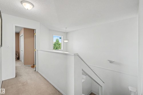 Hallway with neutral carpet, white walls, and a flush-mount ceiling light - 8513 156 Avenue Nw, Edmonton, AB 