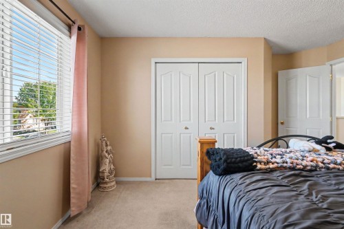 Window with blinds, double bi-fold closet doors, wall-to-wall carpeting, and a neutral wall color - 8513 156 Avenue Nw, Edmonton, AB 