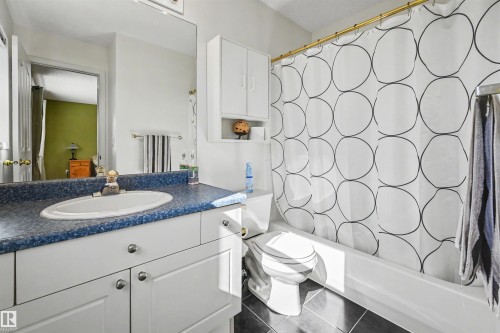 White vanity with integrated sink, blue speckled countertop, and tiled flooring - 8513 156 Avenue Nw, Edmonton, AB 