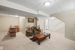 Recessed lighting, drop ceiling, carpet flooring, painted walls, and a finished staircase with white balusters - 