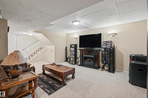 Finished living space featuring carpeting and a built-in fireplace with a dark wood-finish surround - 8513 156 Avenue Nw, Edmonton, AB 