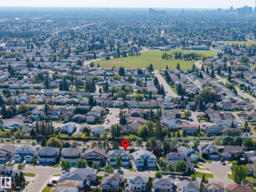 Suburban neighborhood featuring residential homes, mature trees, and a distant city skyline - 8513 156 Avenue Nw, Edmonton, AB 