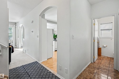 Archway entryways, wood-finish flooring, white painted walls, and tiled bathroom flooring - 8513 156 Avenue Nw, Edmonton, AB 