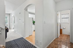 Archway entryways, wood-finish flooring, white painted walls, and tiled bathroom flooring - 