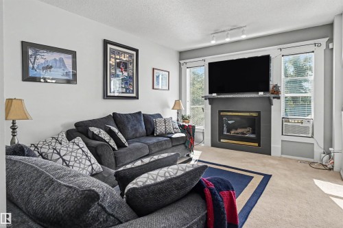 Built-in fireplace with a dark surround, flanked by two windows - 8513 156 Avenue Nw, Edmonton, AB 
