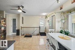 Neutral-toned tile flooring, stainless steel refrigerator, white paneled door with frosted glass, ceiling fan with integrated lighting, and a window with horizontal blinds - 
