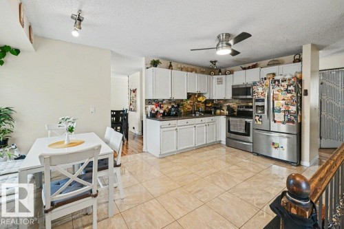 Kitchen featuring white cabinetry, stainless steel appliances, and a tiled backsplash - 8708 25A Avenue Nw, Edmonton, AB 