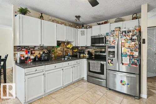 White cabinetry, stone tile backsplash, stainless steel appliances, tile flooring, and a ceiling fan - 8708 25A Avenue Nw, Edmonton, AB 