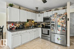 White cabinetry, stone tile backsplash, stainless steel appliances, tile flooring, and a ceiling fan - 