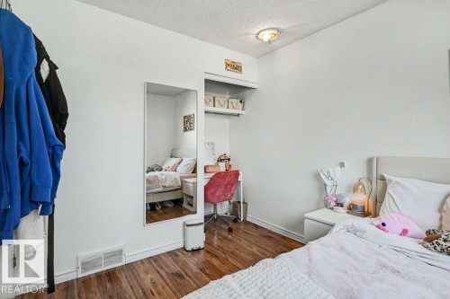 Wood-finish flooring with white baseboards, built-in shelving, and a simple ceiling light fixture - 8708 25A Avenue Nw, Edmonton, AB 
