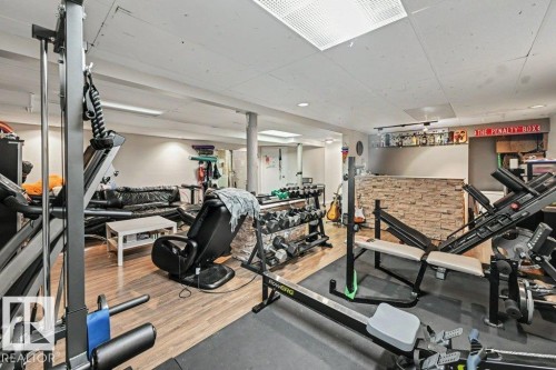 Wood-finish flooring throughout, featuring a stone-clad bar with shelving - 8708 25A Avenue Nw, Edmonton, AB 