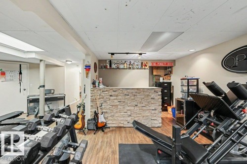 Recessed lighting, wood-finish flooring, stone-clad bar, track lighting, and a drop ceiling - 8708 25A Avenue Nw, Edmonton, AB 