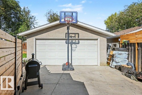 Detached garage with a paneled garage door and a textured stucco exterior - 8708 25A Avenue Nw, Edmonton, AB 
