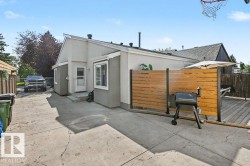 Exterior featuring light gray siding, white trim, a concrete patio, and a wood deck with privacy screening - 