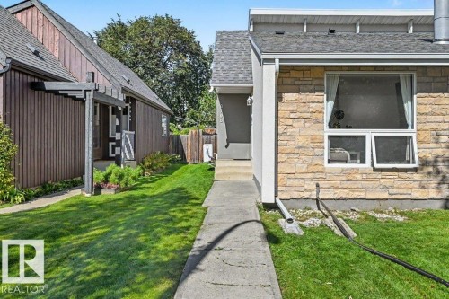 Stone veneer exterior with a concrete pathway and lush green lawn - 8708 25A Avenue Nw, Edmonton, AB 