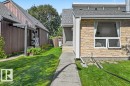 Stone veneer exterior with a concrete pathway and lush green lawn - 8708 25A Avenue Nw, Edmonton, AB 