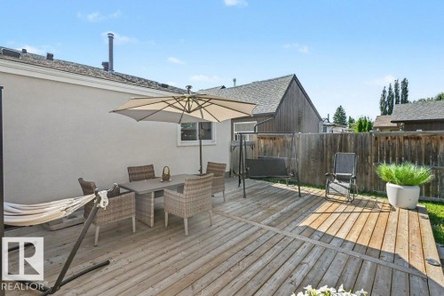 Expansive wood-finish deck with privacy fencing and a stucco exterior - 8708 25A Avenue Nw, Edmonton, AB 