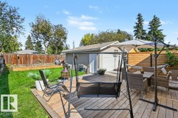 Expansive backyard with a wood-finish deck, lush lawn, wood fencing, and a detached garage featuring a white overhead door - 