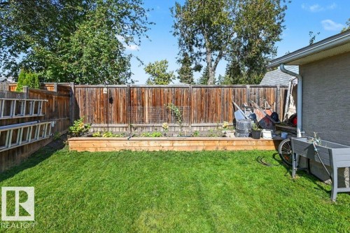 Manicured lawn, wood plank fencing, raised garden bed, and stucco exterior - 8708 25A Avenue Nw, Edmonton, AB 