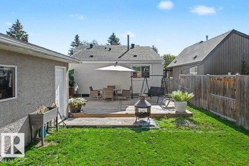 Expansive backyard featuring a manicured lawn, a raised wood deck, and a privacy fence - 8708 25A Avenue Nw, Edmonton, AB 