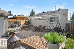 Expansive wood-finish deck with a privacy fence, stucco exterior, and a built-in fire pit - 