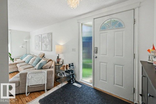 White paneled entry door with an arched decorative glass insert and a frosted glass sidelight - 8708 25A Avenue Nw, Edmonton, AB 