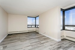 Expansive room featuring wood-finish flooring, light-toned walls, and large windows with black framing - 