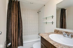 Bathroom featuring a built-in bathtub with tiled surround, vanity with an integrated sink, and wall-mounted mirror - 