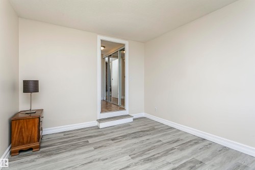 Light-colored walls, wood-finish flooring, white trim, and a recessed doorway with mirrored closet doors - #815 10160 114 St Nw, Edmonton, AB 