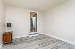 Light-colored walls, wood-finish flooring, white trim, and a recessed doorway with mirrored closet doors - 
