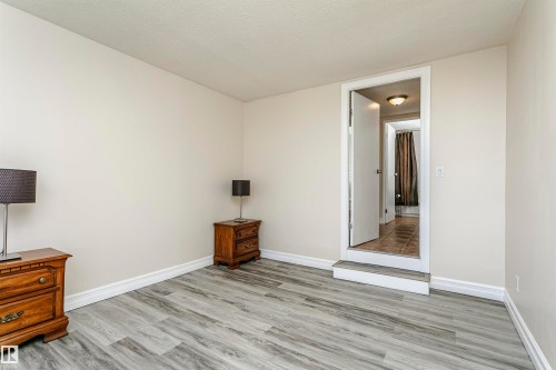 Wood-finish flooring with white trim, leading to a doorway with a raised threshold - #815 10160 114 St Nw, Edmonton, AB 