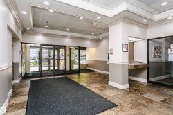 Entry foyer featuring large format tile flooring, crown molding, recessed lighting, glass entry doors, and an integrated reception desk - 