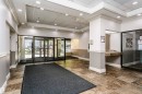 Entry foyer featuring large format tile flooring, crown molding, recessed lighting, glass entry doors, and an integrated reception desk - #815 10160 114 St Nw, Edmonton, AB 