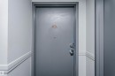 Gray entry door with a brass-finish number plaque, peephole, and silver-tone hardware - #815 10160 114 St Nw, Edmonton, AB 