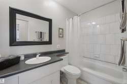 White vanity with a dark countertop, an oval undermount sink, and a framed mirror - 