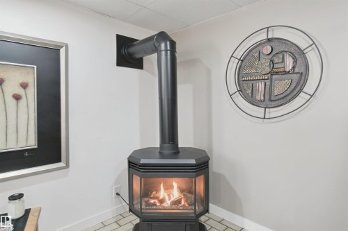 Freestanding gas fireplace with a black finish, glass panels, and a visible flue pipe - 11439 144 Avenue Nw, Edmonton, AB 