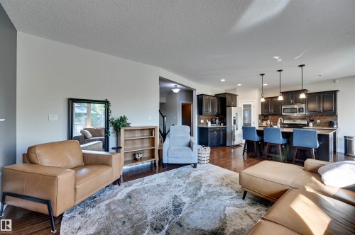 Hardwood-finish flooring throughout, dark wood cabinetry, stainless steel appliances, and pendant lighting - 2203 Warry Loop Sw, Edmonton, AB 