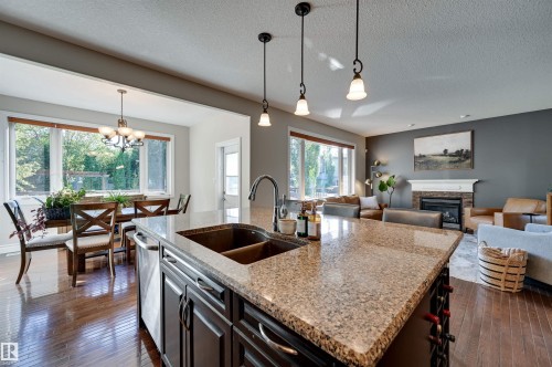 Kitchen island with a double basin sink, granite countertop, and dark wood-finish cabinetry - 2203 Warry Loop Sw, Edmonton, AB 