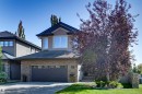 Two-story residence featuring stucco and stone veneer exterior, a dark shingle roof, attached garage with frosted-panel door, and a concrete driveway - 2203 Warry Loop Sw, Edmonton, AB 