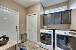 Laundry area featuring dark wood-finish cabinetry, a stone-finish countertop, and tile flooring - 