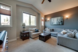 Vaulted ceiling with a ceiling fan, multiple windows with blinds, recessed wall sconces, and neutral tone carpet flooring - 
