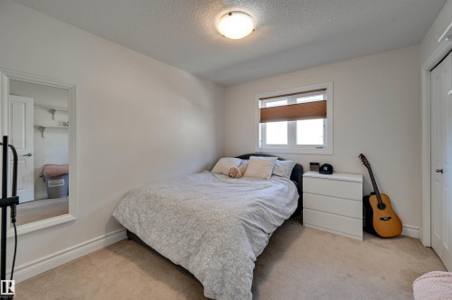Carpeted room featuring a double-paned window, neutral wall tones, and a built-in closet with a white panel door - 2203 Warry Loop Sw, Edmonton, AB 