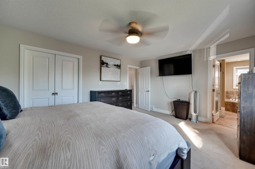 Neutral wall paint, ceiling fan, carpet flooring, double-panel interior doors, and a built-in tub with tile surround - 2203 Warry Loop Sw, Edmonton, AB 