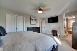 Neutral wall paint, ceiling fan, carpet flooring, double-panel interior doors, and a built-in tub with tile surround - 